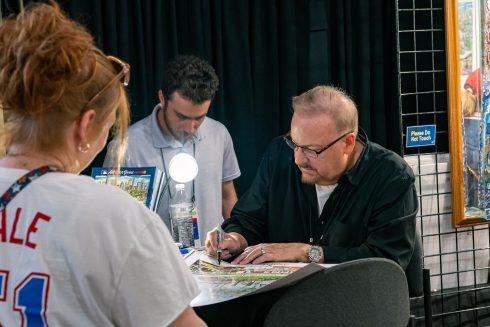 Fazzino signing posters at the All-Star Village
