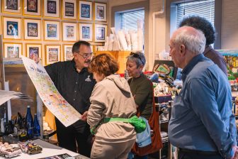 A group of people gather to look more closely at Fazzino artwork and how it gets created