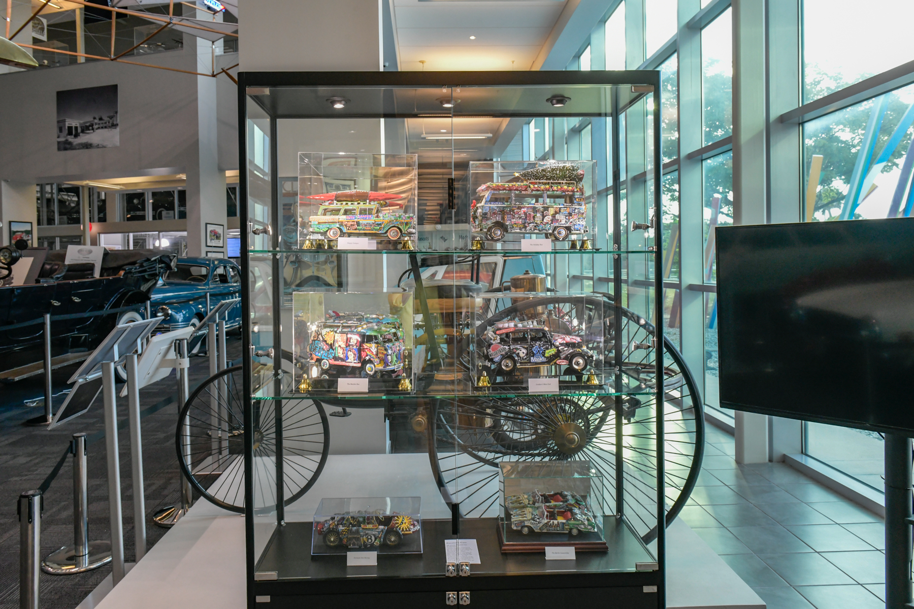 A display case full of Fazzino's car sculptures include a VW bus and a wagoneer