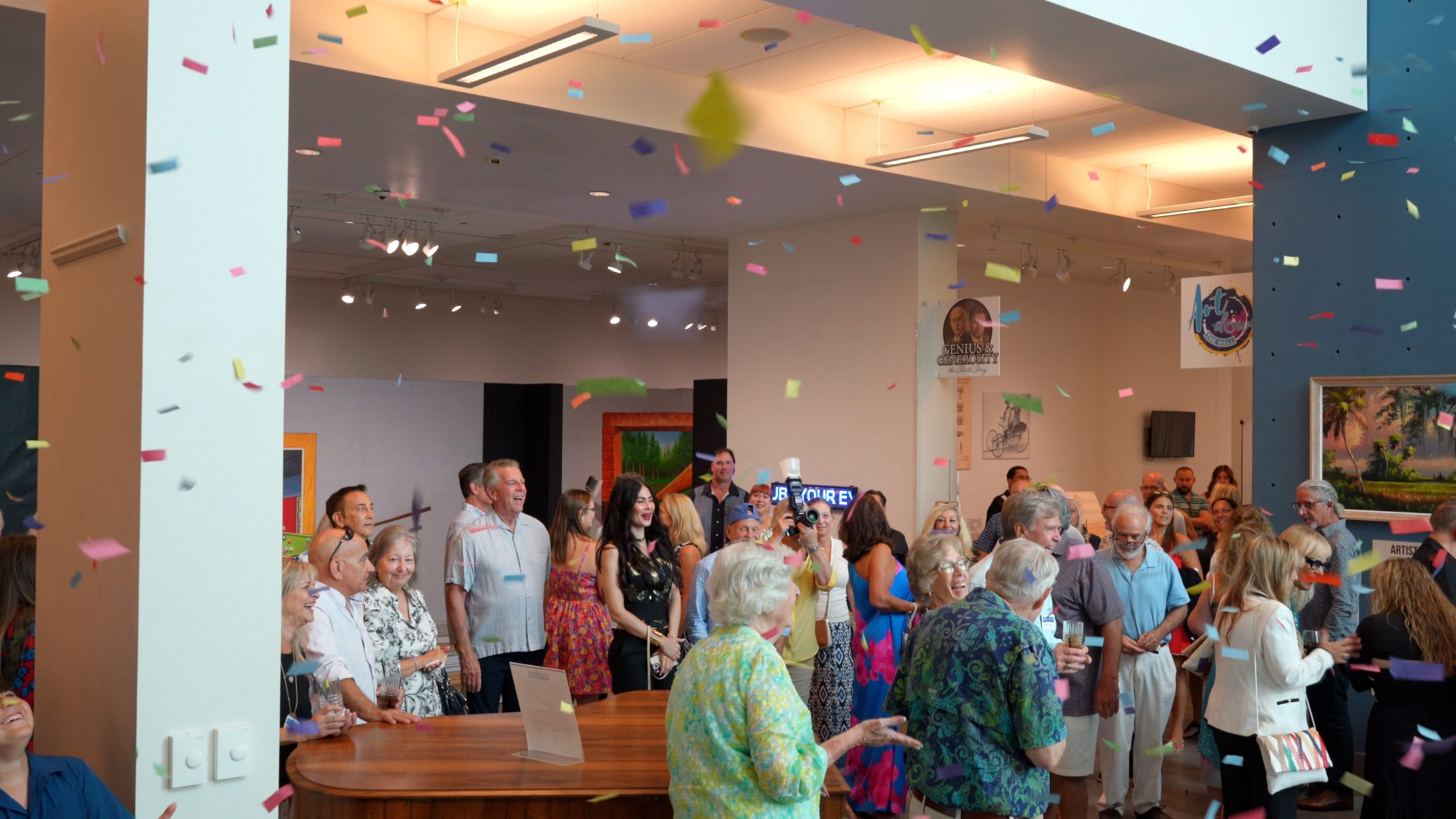 Confetti flies in the air and attendees at the VIP event smile with job as they get ready to see the Fazzino retrospective