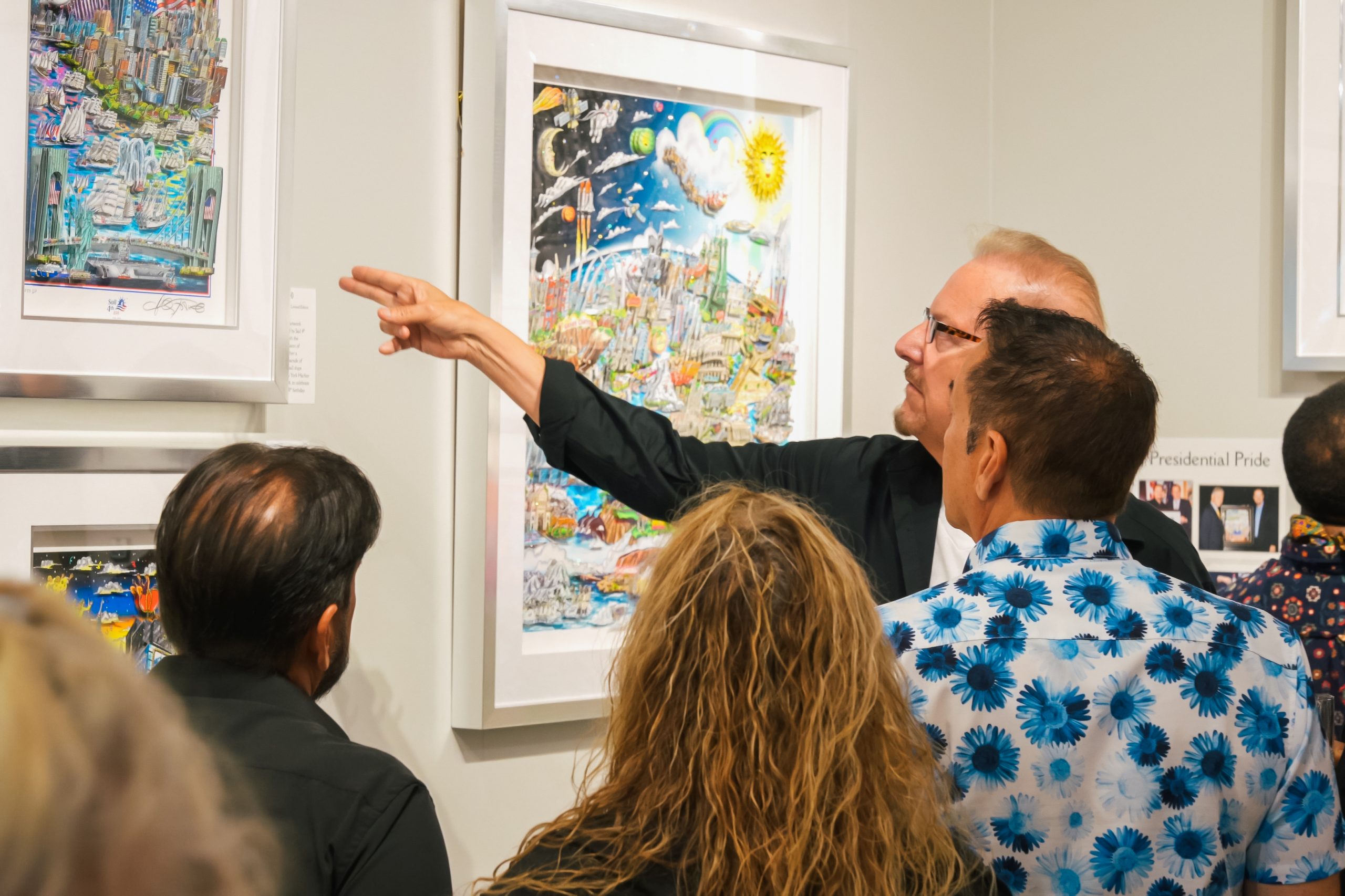 Fazzino points to his artwork telling stories about it's contents to the fans that gather around to listen